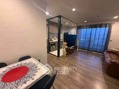 Modern open-plan living room with stylish decor and glass partitioned kitchen.