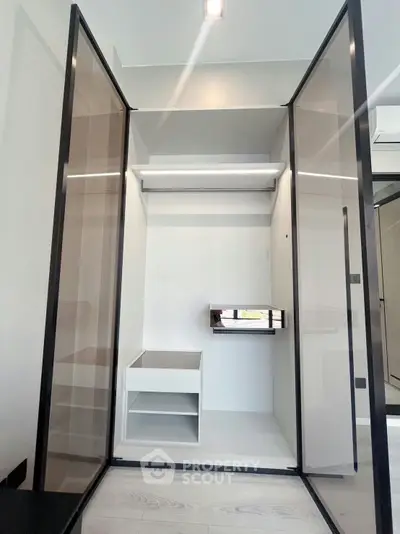 Modern walk-in closet with sleek glass doors and built-in shelving