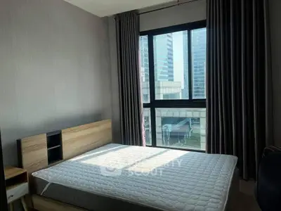 Modern bedroom with large windows offering ample natural light and a view of the city, featuring a spacious bed and contemporary design.