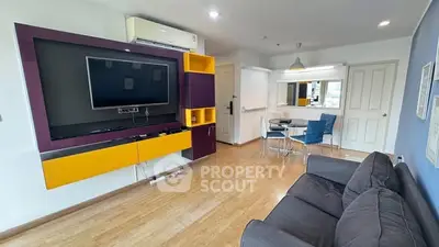 Modern living room with vibrant TV unit and cozy seating area in a stylish apartment.