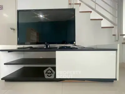 Modern living room with sleek TV stand and staircase, perfect for contemporary home design.