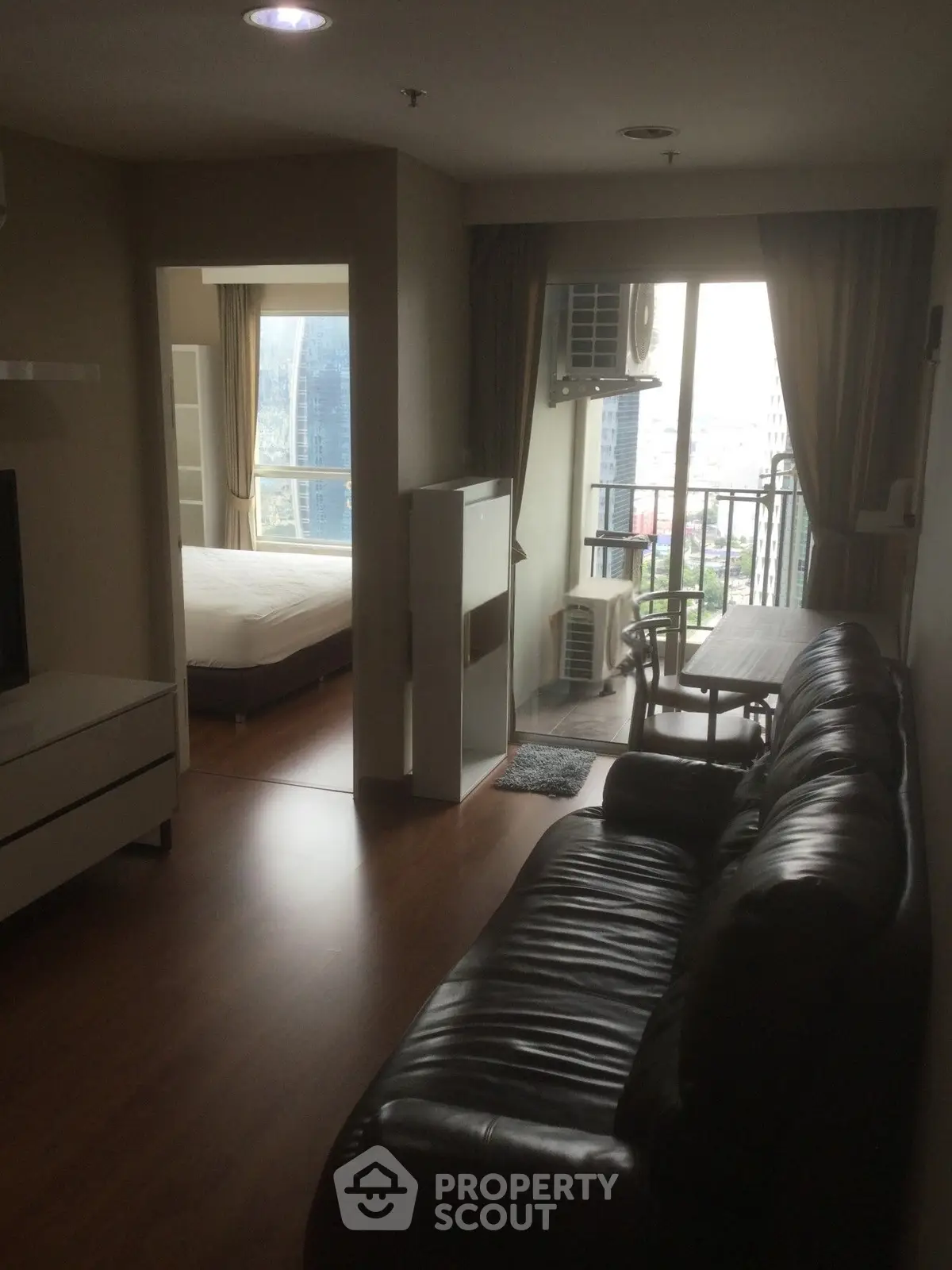 Modern apartment living room with leather sofa and city view balcony