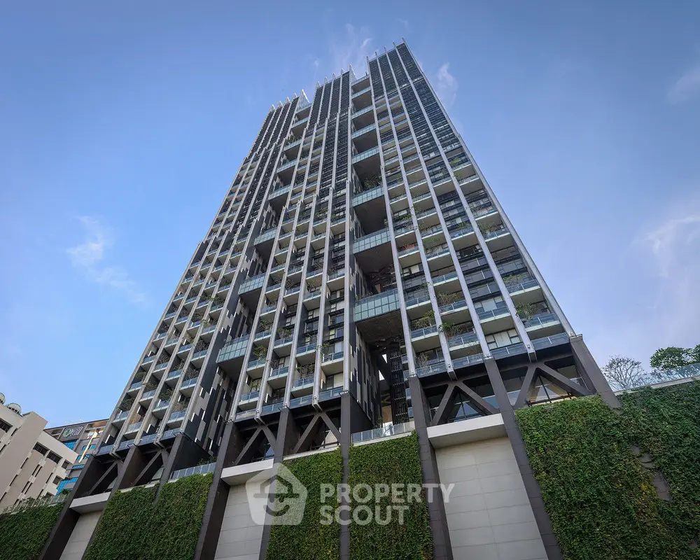 Stunning modern high-rise building with lush green facade and clear blue sky