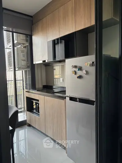 Modern kitchen with sleek cabinetry and stainless steel fridge in a compact apartment setting.