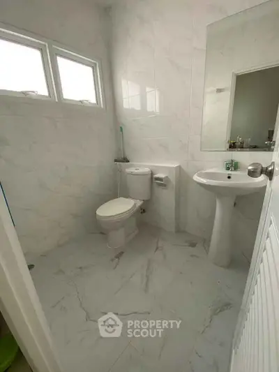 Modern bathroom with white marble tiles and pedestal sink
