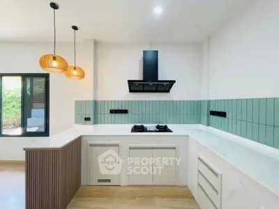 Modern kitchen with sleek design, featuring gas stove and stylish pendant lights, perfect for culinary enthusiasts.