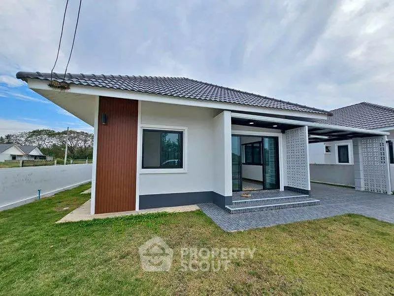 Modern single-story house with tiled roof and spacious lawn, perfect for family living.