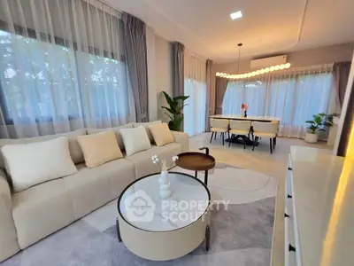 Elegant living room with modern decor and large windows, featuring a cozy seating area and stylish dining space.