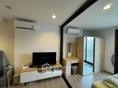 Modern bedroom with TV, air conditioning, and balcony view in stylish apartment.