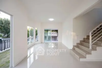 Spacious modern living room with large windows and staircase, perfect for natural light lovers.