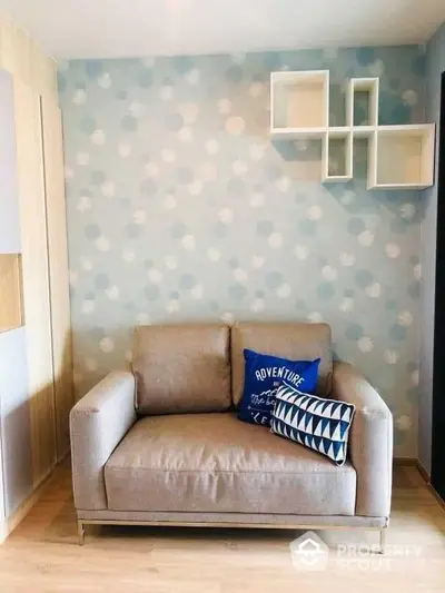 Cozy and stylish living space with a modern beige sofa against a playful polka dot wall, complemented by chic white floating shelves.