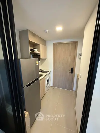 Compact kitchen with modern appliances and wooden cabinetry in a cozy apartment.