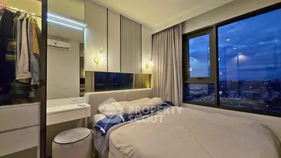 Modern bedroom with large windows offering stunning city views at dusk.
