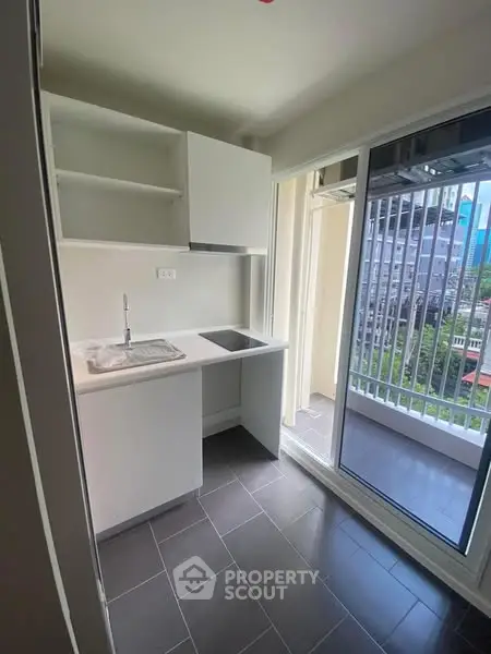 Modern compact kitchen with balcony view in urban apartment