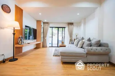 Spacious living room with modern decor and large sofa, featuring wooden flooring and natural light.