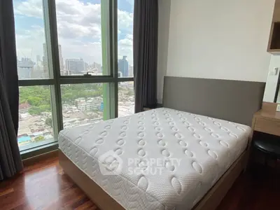 Modern bedroom with city view and large window in high-rise apartment.