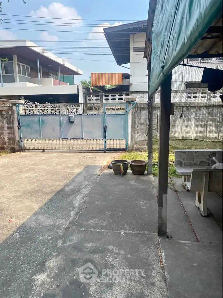 Spacious outdoor area with concrete flooring and gated entrance, ideal for parking or outdoor activities.