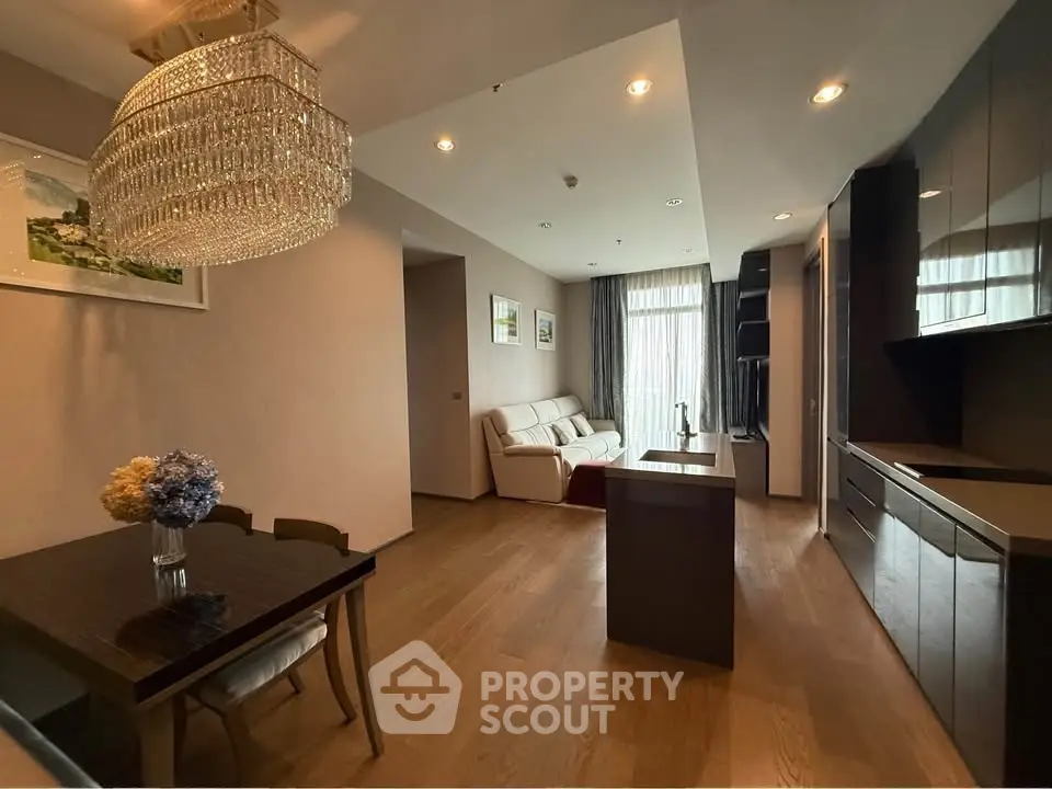 Elegant open-plan living room with chandelier and modern kitchen