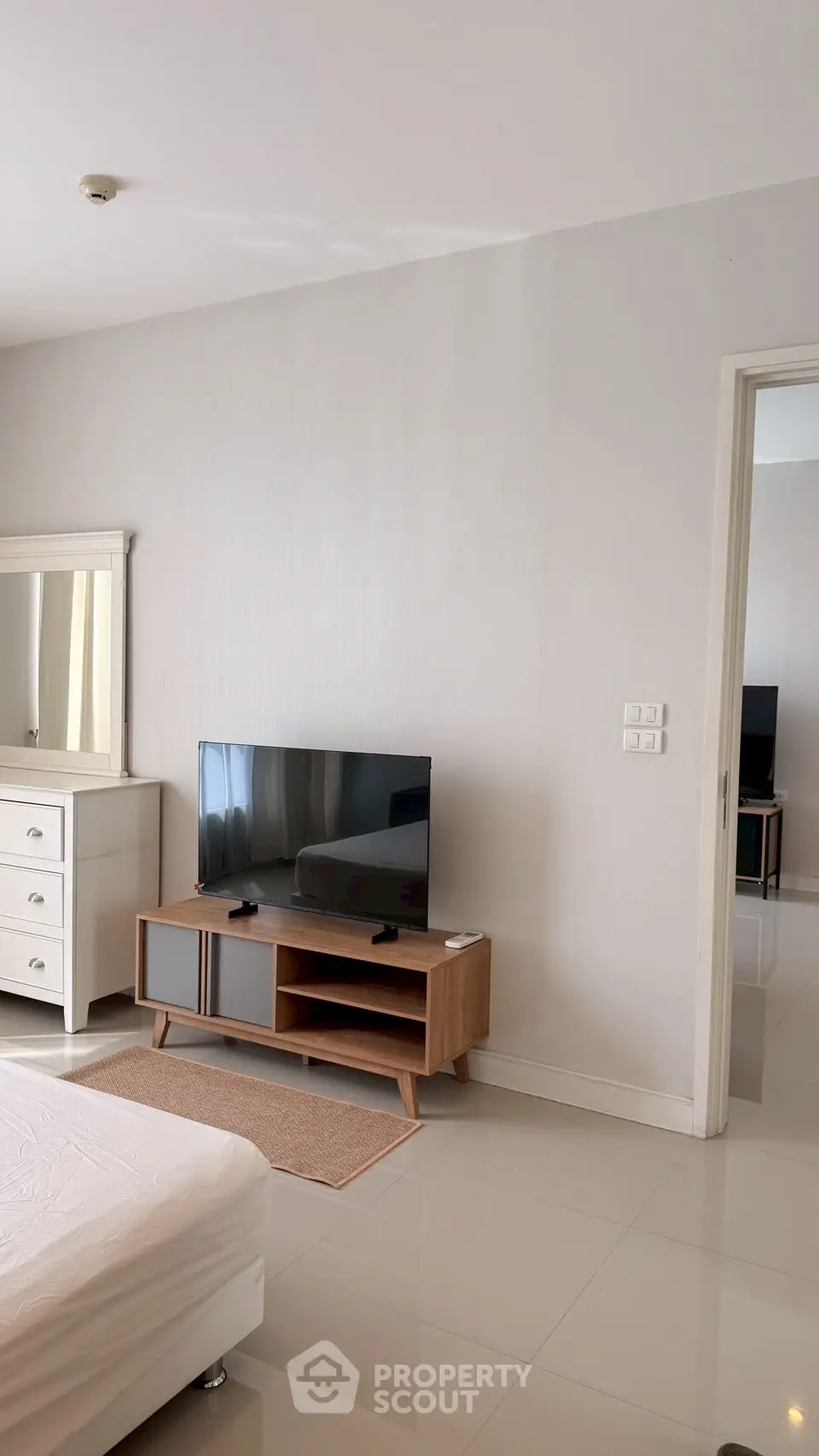 Modern bedroom with sleek TV stand and dresser, showcasing minimalist design and bright ambiance.
