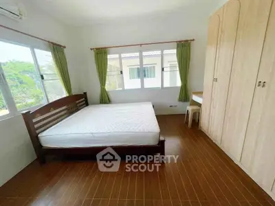 Spacious bedroom with large windows and wooden furniture in a bright, airy home.