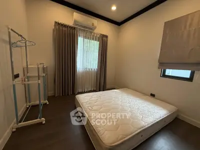 Minimalist bedroom with mattress and window, featuring modern lighting and neutral tones.