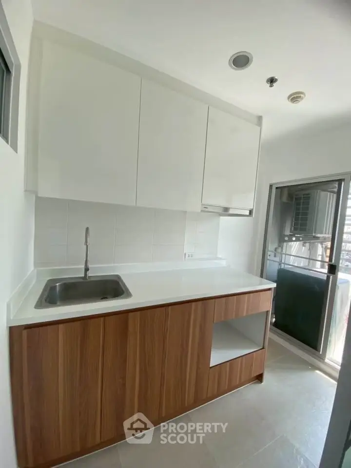 Modern kitchen with sleek cabinetry and balcony access in a bright apartment.