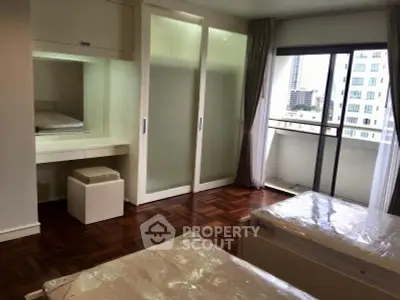 Spacious bedroom with balcony in modern apartment, featuring parquet flooring and ample natural light.
