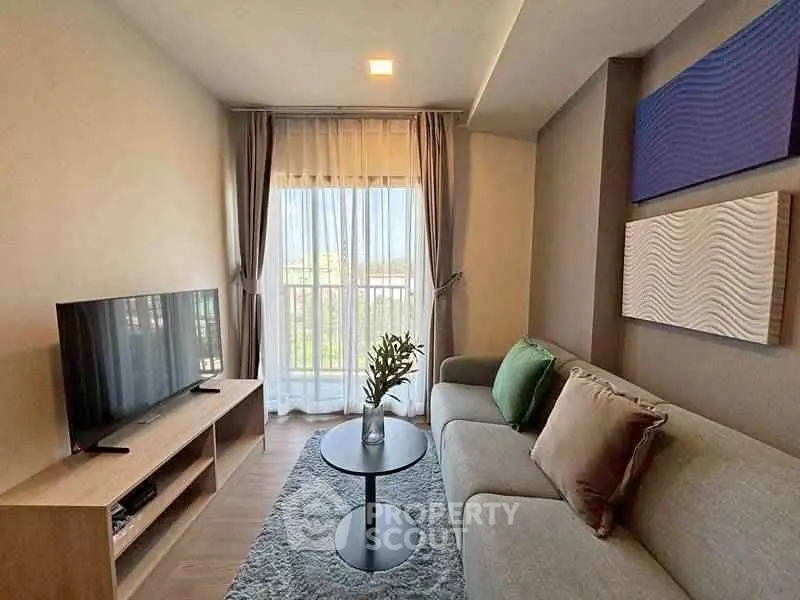 Modern living room with cozy sofa and large TV, featuring elegant decor and natural light.