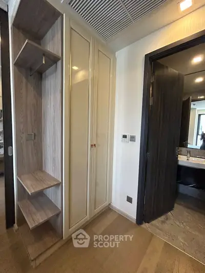 Modern apartment interior with wooden flooring and built-in storage near bathroom entrance.
