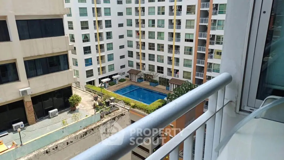 Stunning view from balcony overlooking modern apartment complex with pool and lush greenery.