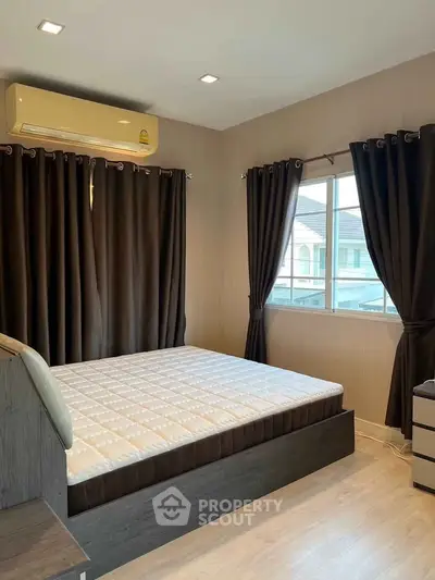 Cozy bedroom with large window and modern furnishings in a stylish home.