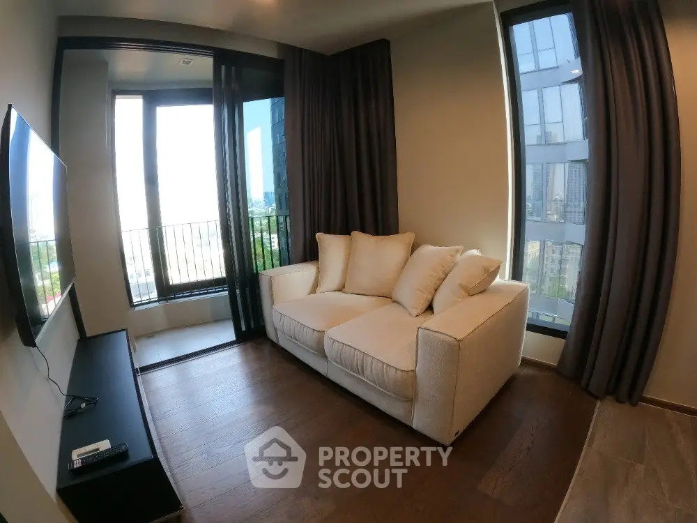 Modern living room with cozy sofa and large windows offering city views, perfect for relaxation.