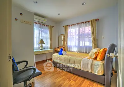 Cozy bedroom with wooden flooring, single bed, and study desk, perfect for a serene living experience.