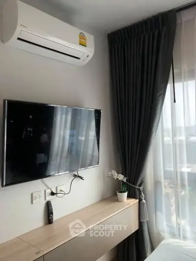 Modern bedroom with wall-mounted TV and air conditioning, featuring elegant curtains and a sleek design.