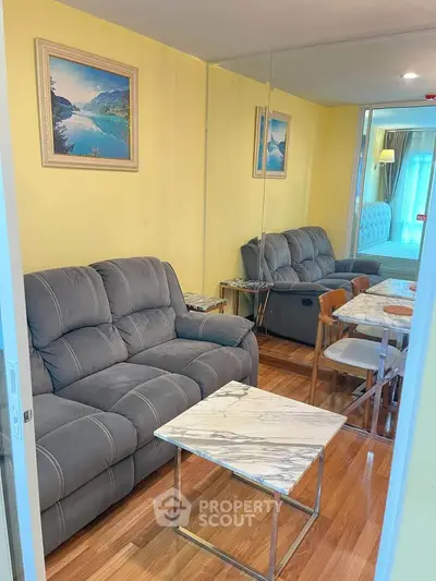 Cozy living room with plush gray sofas, marble tables, and wooden flooring, perfect for relaxation.