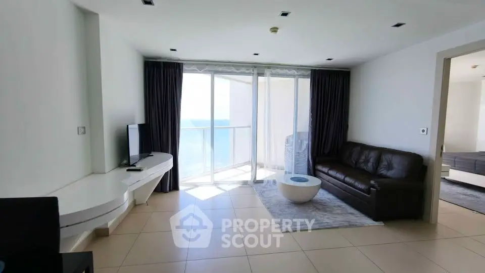 Modern living room with ocean view, sleek furniture, and abundant natural light in a luxury apartment.
