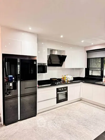 Modern kitchen with sleek white cabinetry, black countertops, and built-in appliances for a stylish cooking space.