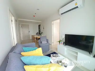 Bright and airy living room with modern furnishings, sleek TV unit, and a cozy dining area in the background, perfect for urban living.