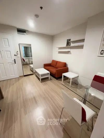 Modern living room with wooden flooring, orange sofa, and glass dining table in a cozy apartment.
