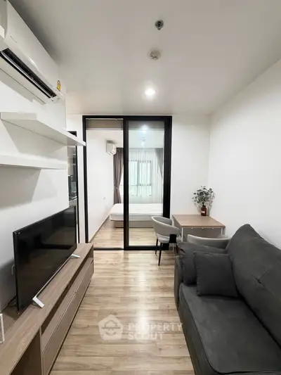Modern living room with sleek furniture and open view to bedroom