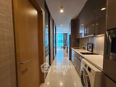 Modern kitchen with sleek appliances and open layout leading to living area.