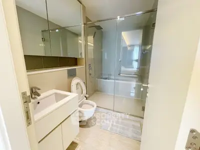 Modern bathroom with glass shower and sleek fixtures in luxury apartment.