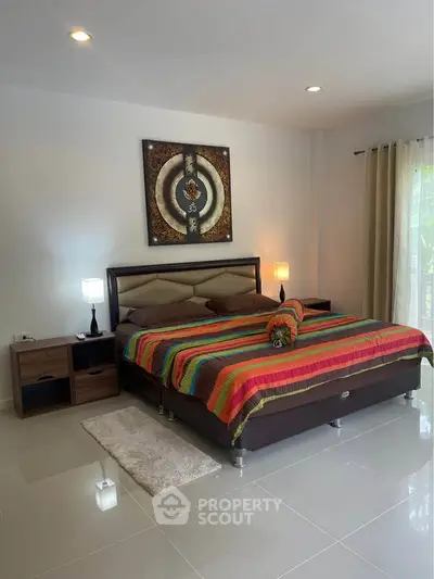 Spacious bedroom with colorful bedding and modern decor in a bright, inviting setting.