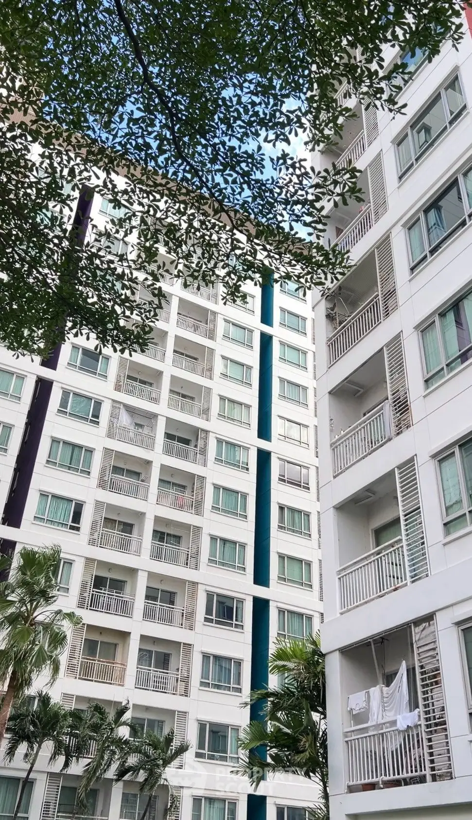 Modern high-rise apartment building with balconies and lush greenery, perfect for urban living.