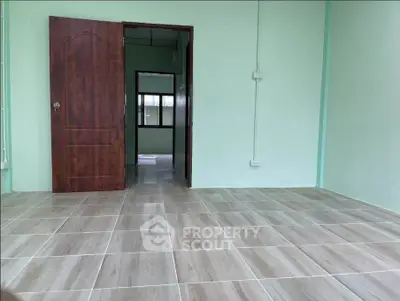 Spacious empty room with tiled flooring and wooden door, ready for customization.