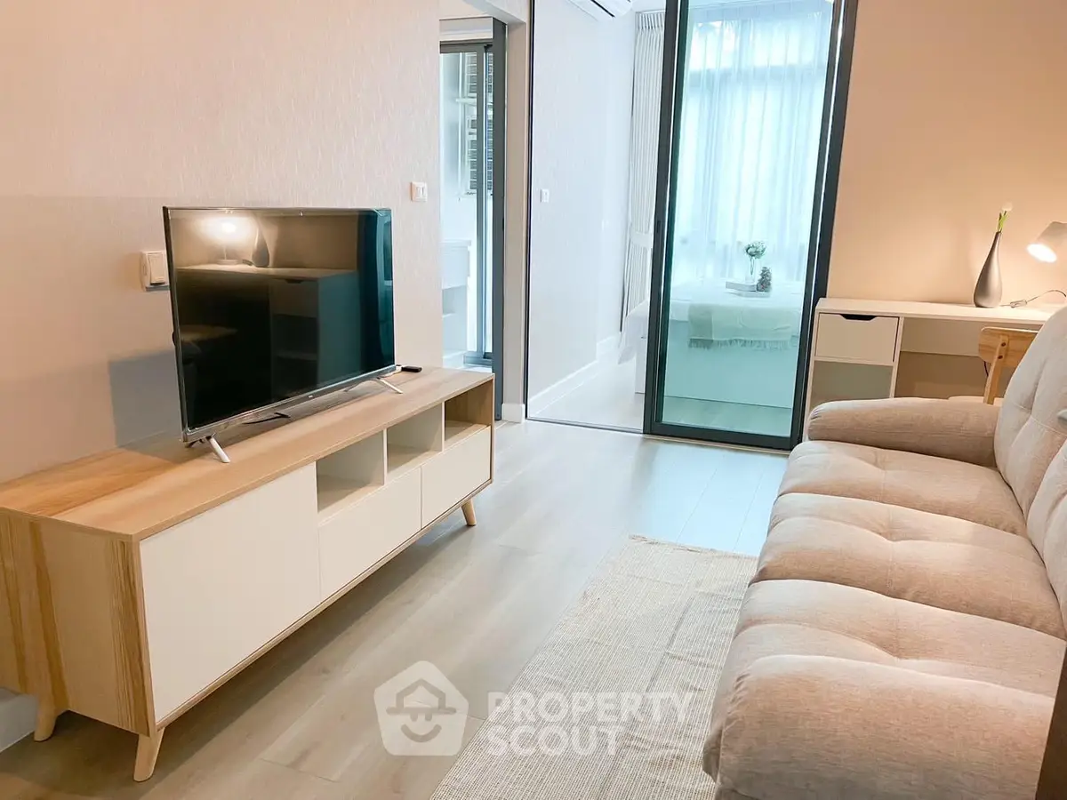 Modern living room with sleek furnishings and access to a bright balcony, perfect for urban living and entertaining guests.