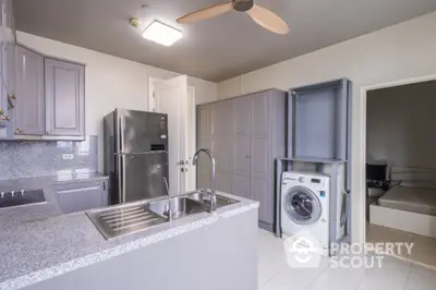 Modern kitchen with sleek appliances and washing machine, featuring granite countertops and ample storage space.