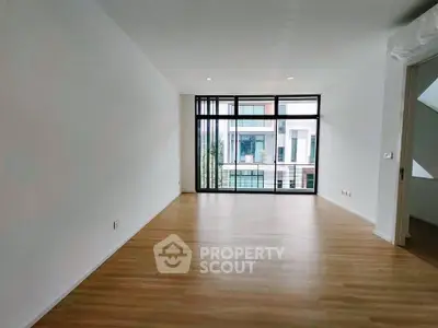 Spacious modern living room with large windows and wooden flooring, perfect for natural light lovers.