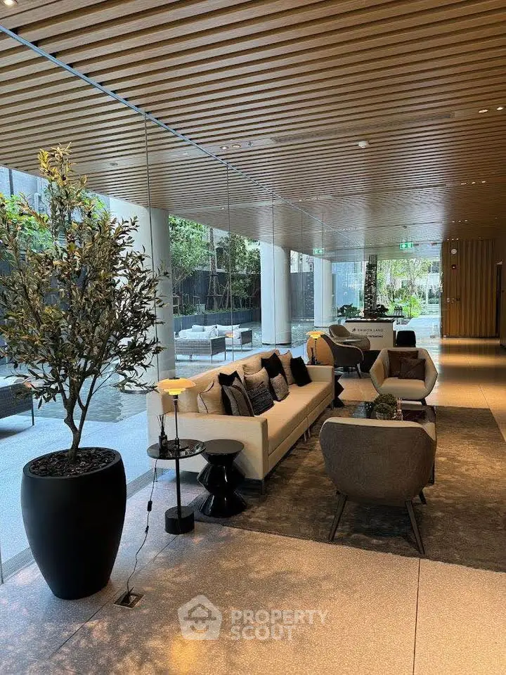 Luxurious modern lobby with elegant seating and greenery, featuring floor-to-ceiling windows and stylish decor.