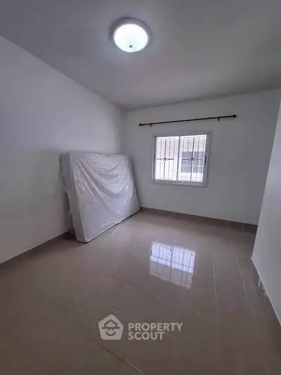 Spacious unfurnished room with tiled flooring and natural light from window.
